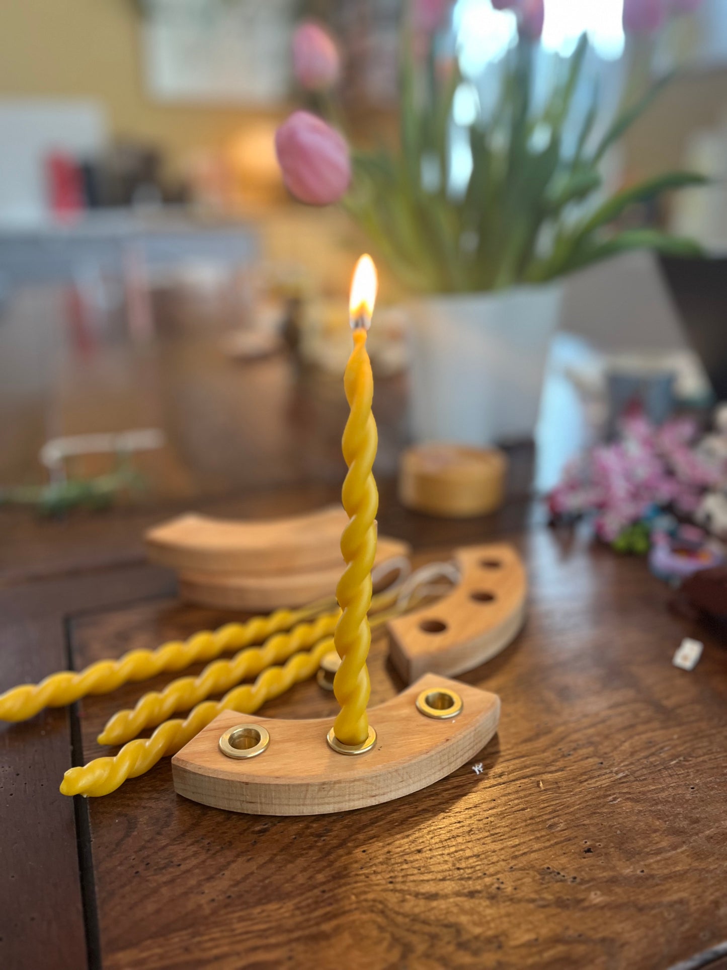 To bivokslys som er tvinnet sammen til et vakkert festlys. Lyset står å brenner i et lysestake bursdagsring fra GRIMMS.