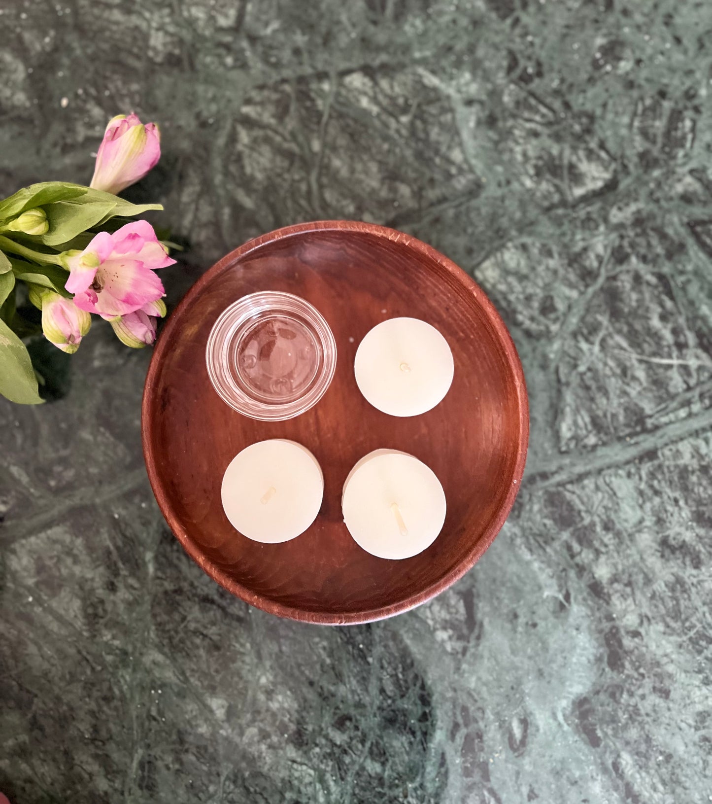 Tre telys av ren bivoks i fargen naturhvit og en telysholder som ligger utstilt på et bord. 