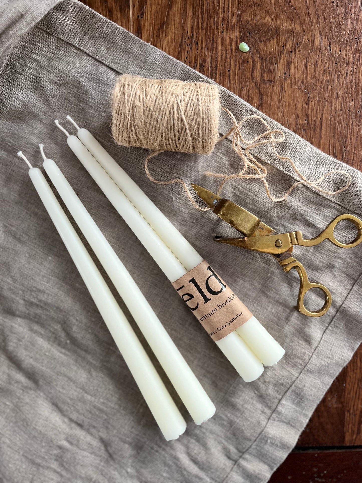 Bivoks kronelys i naturhvit farge som ligger på et bord. 